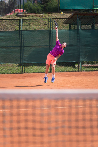 Young tennis player serving the ball - Fotoğraf, Görsel