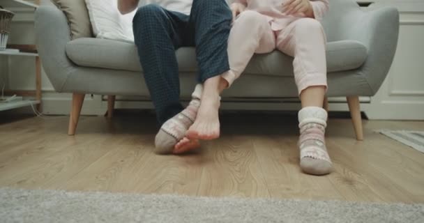 Fun time for a couple at home on the sofa playing with legs , in pajamas closeup capturing playing legs. 4k - Filmagem, Vídeo