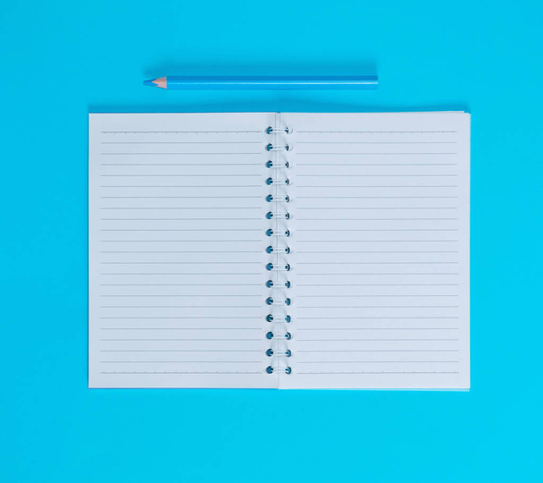 Notitieboekje met lege witte lakens in lijn en blauwe houten potlood, blauwe achtergrond, bovenaanzicht - Foto, afbeelding