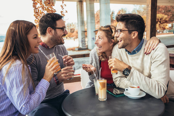 Gruppo di quattro amici che si divertono a prendere un caffè insieme. Due donne e due uomini al caffè a parlare ridendo e godendo il loro tempo - Foto, immagini