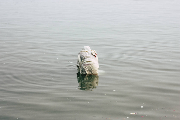 Varanasi India November 10, 2018 View of unknown old Indian woman praying in the Ganges river at Varanasi in the afternoon - Foto, Bild