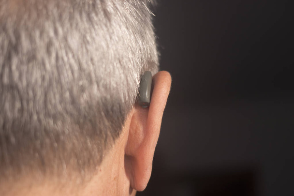 Deaf Seniorów człowiek sobie cyfrowej wysokiej technologii aparatu słuchowego do ucha. - Zdjęcie, obraz