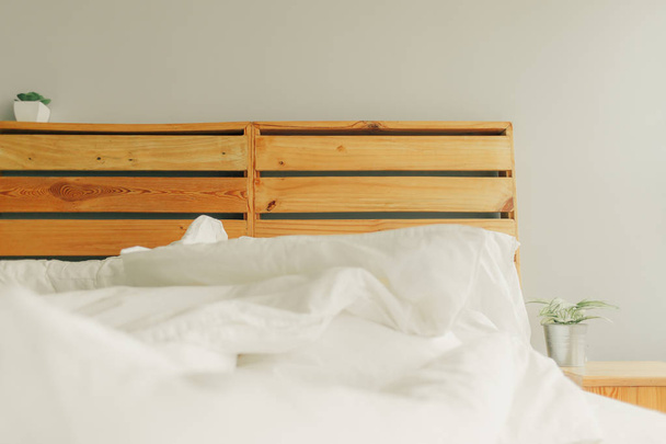 Loft style unmaking white bed with wooden headboard. - Fotó, kép