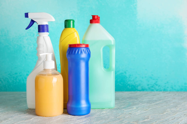 Бутылки с моющими средствами на столе на цветном фоне
 - Фото, изображение