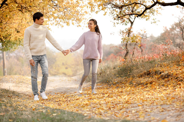 Couple in love walking and enjoying beautiful autumn day in park. smiling man and woman holding hands. happy moments of life. - Фото, изображение