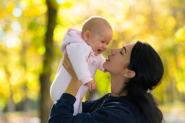 Rakastava äiti leikkii onnellisella, nauravalla vauvallaan puistonäkymässä kauniilla, kirkkaalla syysvalolla.
. - Valokuva, kuva
