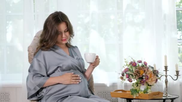 Viehättävä raskaana oleva nainen kupin teetä
 - Materiaali, video