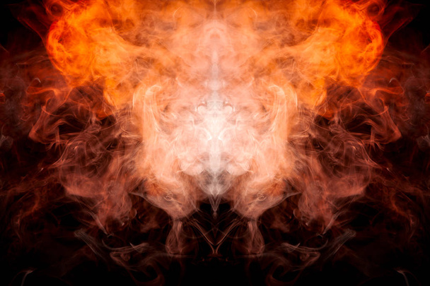 Um fundo de laranja e amarelo fumaça ondulada na forma de uma cabeça de fantasma ou um homem de aparência mística em um solo isolado preto. Padrão abstrato brilhante de vapor de vape
. - Foto, Imagem