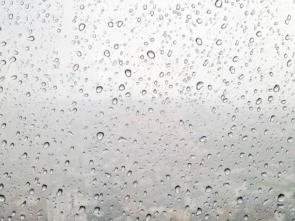 Gotas de lluvia en la superficie de los cristales de la ventana mientras llueve fuerte que ver en fondo borroso
 - Foto, Imagen