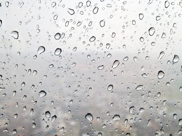 Gotas de lluvia en la superficie de los cristales de la ventana mientras llueve fuerte que ver en fondo borroso
 - Foto, imagen