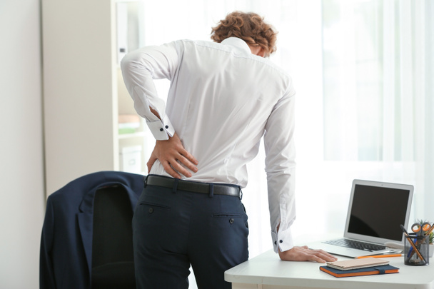 Νέος επιχειρηματίας που πάσχουν από τον πόνο στην πλάτη στο γραφείο - Φωτογραφία, εικόνα