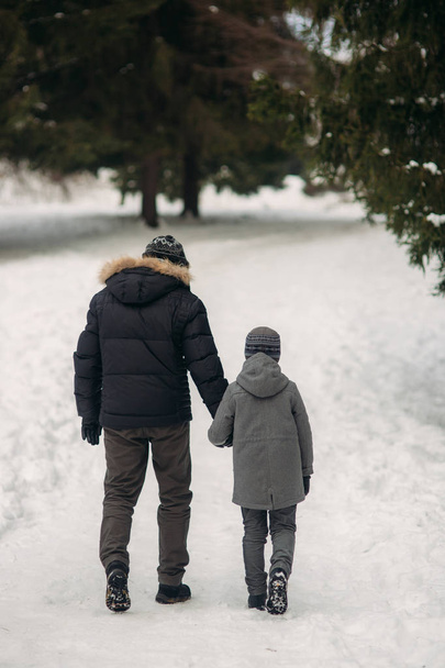 Happy father with his son walks through the park in the snowy winter weather - Fotó, kép