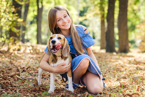 Little smiling blond girls sit hugging beagle dog - Foto, afbeelding