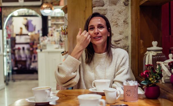 Ładna kobieta, siedząc w kawiarni i rozmawiając z języka migowego. Portret pani wyrażając "czyste". - Zdjęcie, obraz