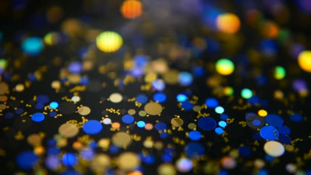 Defocused shimmering multicolored glitter confetti, black background. Holiday abstract festive bokeh light spots. - Footage, Video