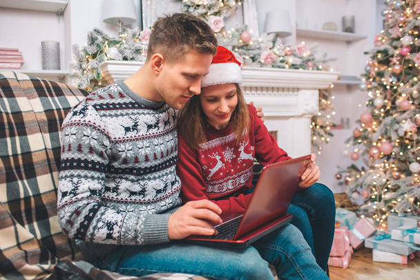 Concentrated and interested young man and woman works using laptop. They look at it. Guy pushes buttons. They wear festive clothes. - 写真・画像