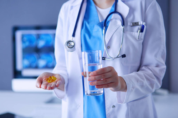 shot of doctors hands holding pills and glass of water at clinic. - Foto, immagini