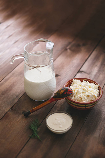 Fresh milk, sour cream and cottage cheese on a dark wooden table - Foto, Imagen