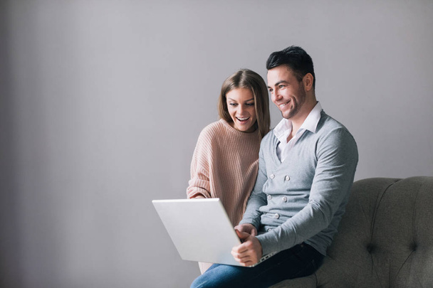 Shopping online together. Beautiful young loving couple using laptop. - Foto, afbeelding