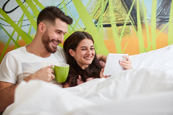 Couple in love in bed with coffee and cell phone in the morning - Foto, imagen