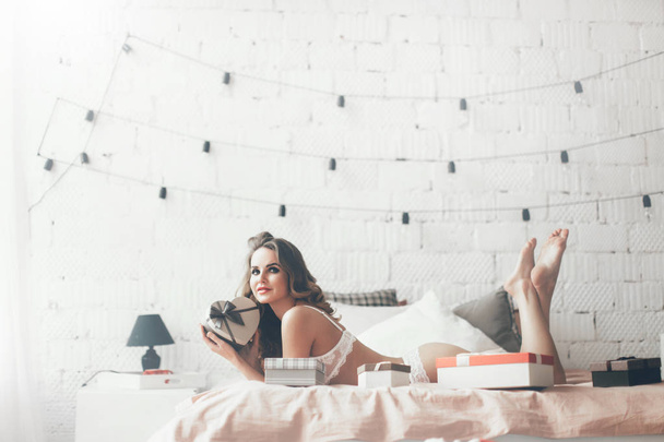 Portrait of beautiful woman in lingerie with gift boxes at home. Celebration. - Fotografie, Obrázek