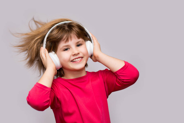 A gyermekek és a technológia koncepció - mosolygó lány, elszigetelt fehér zenehallgatás fejhallgató. Hosszú haj repül a mozgó. - Fotó, kép