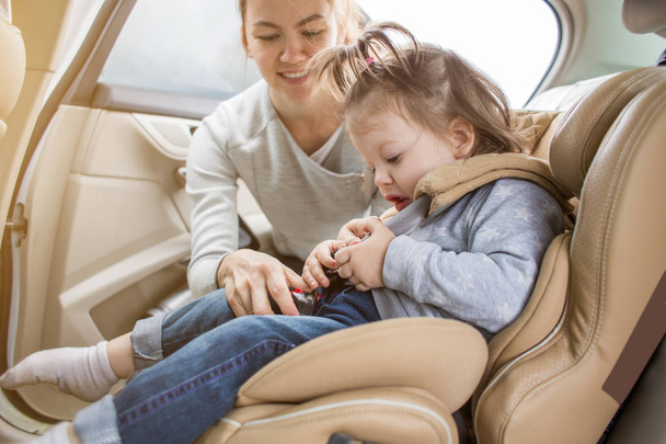 子供のカーシートの赤ちゃん。子供たちの安全な輸送。家族旅行。お母さんが車の座席に彼の子供をクエストします。 - 写真・画像
