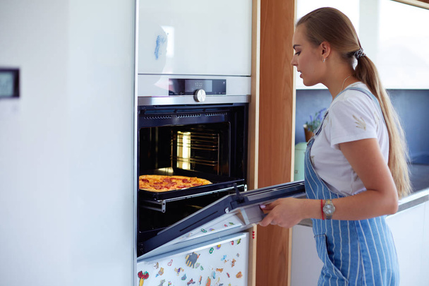 Happy young woman cooking pizza at home - Fotografie, Obrázek