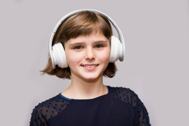 Happy smiling child enjoys listens to music in headphones over white background - Foto, afbeelding