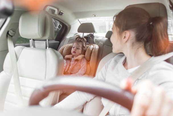 The child in a safety seat near to mother who sits on forward sitting of the car. Baby in a child car seat. safe transportation of children. family travels - Φωτογραφία, εικόνα