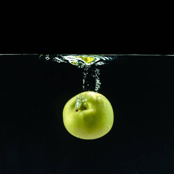 Green apple dropped into water with splash - 写真・画像