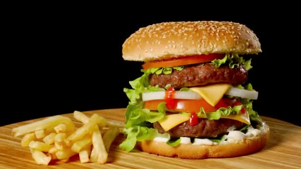 Craft Beef Burger und Pommes frites auf Holztisch isoliert auf schwarzem Hintergrund. - Filmmaterial, Video