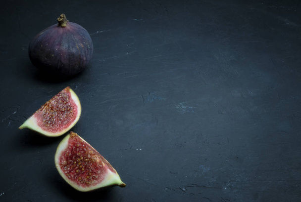 Fresh figs. Food photography. Creative scheme of whole and sliced figs on a dark background, inscribed in a rectangle. Copy space - Фото, изображение