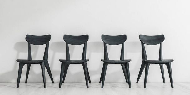 Row of black wooden dining room chairs standing on white wooden floor near white wall. Concept of waiting. 3d rendering - Foto, immagini
