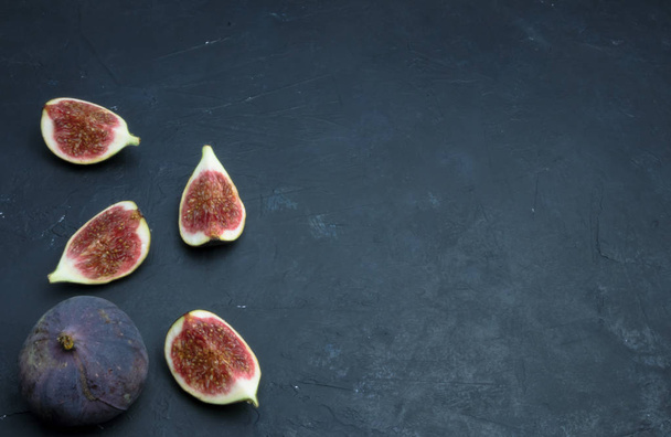 Fresh figs. Food photography. Creative scheme of whole and sliced figs on a dark background, inscribed in a rectangle. Copy space - Фото, зображення