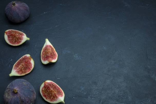 Fresh figs. Food photography. Creative scheme of whole and sliced figs on a dark background, inscribed in a rectangle. Copy space - Фото, изображение