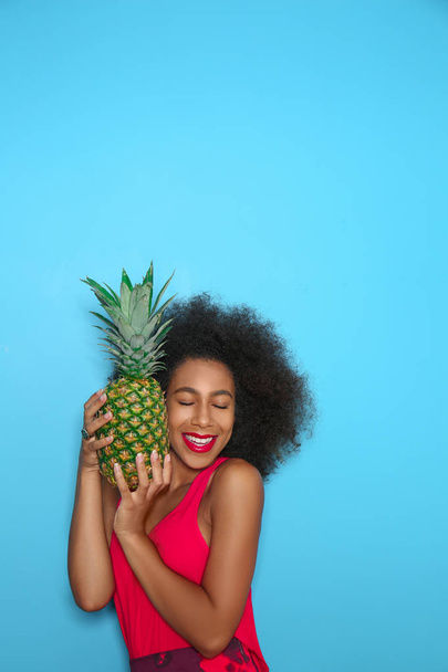 Piękna Afroamerykanka z ananasem na tle koloru - Zdjęcie, obraz