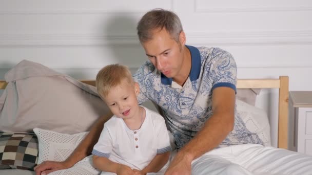 Mies pojan kanssa katsomassa kannettavaa sängyllä
 - Materiaali, video