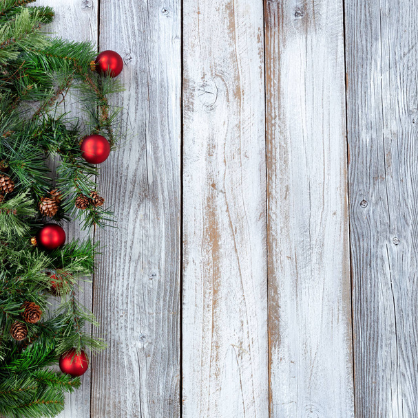 Christmas background with evergreen branches and red ornaments on white rustic wood  - Foto, imagen