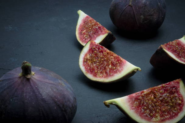 Fresh figs. Food photography. Creative scheme of whole and sliced figs on a dark background, inscribed in a rectangle. - Fotó, kép