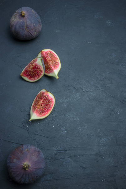 Fresh figs. Food photography. Creative scheme of whole and sliced figs on a dark background, inscribed in a rectangle. Copy space - Photo, image