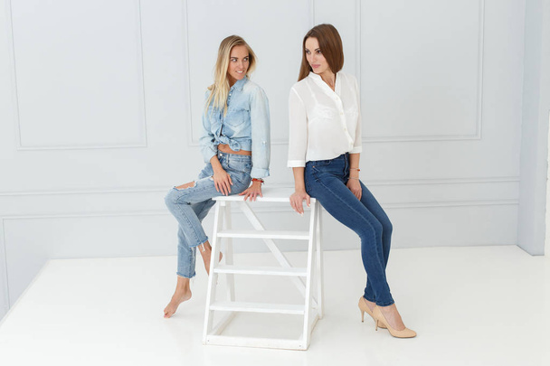 Fashion portrait of women in jeans in light studio background - Foto, Imagem