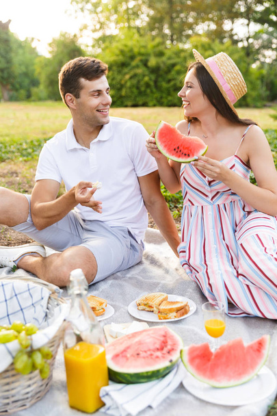 Smiling young couple spending good time together, having picnic at the park - Foto, imagen