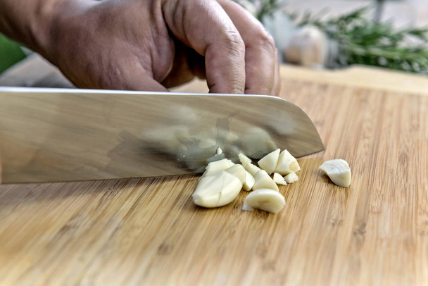 Kezében a cook, fokhagyma aprító késsel a daraboló-board - Fotó, kép