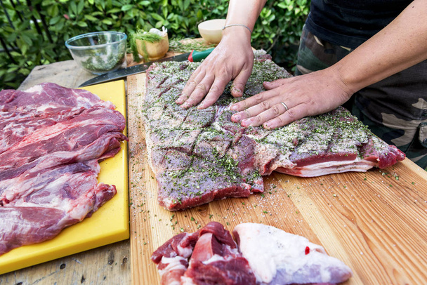 Butcher seasoned meat with salt and herbs for rolled up porchetta - Photo, Image