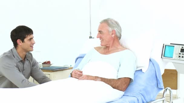 Grandson and father visiting a senior man recovering in hospital - Felvétel, videó