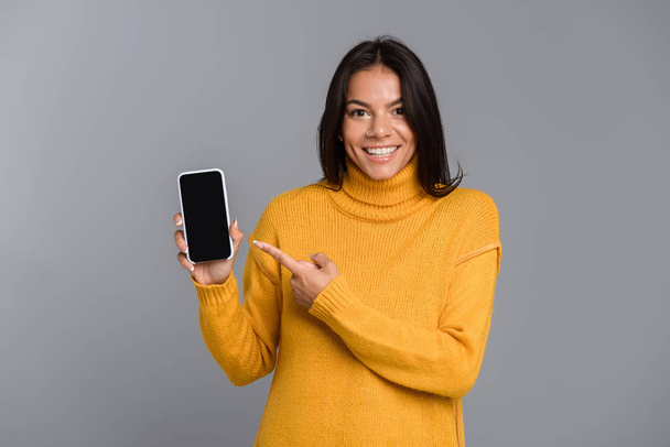 Image of amazing excited woman posing isolated over grey wall background showing display of mobile phone. - Photo, Image