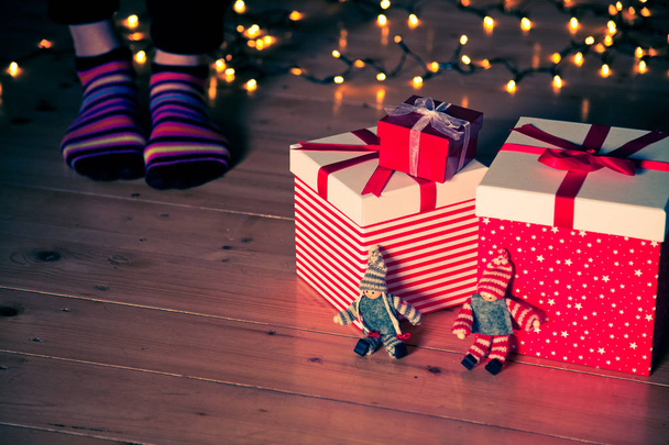 cajas de regalo rojas pies y luces de Navidad en el suelo de madera
 - Foto, imagen