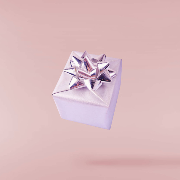 Christmas concept.  Creative Christmas conception made by falling in air silver gift box over pink background. Minimal concept - Фото, изображение
