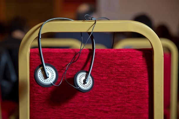 Eş zamanlı çeviri için kulaklıklar. Kablosuz çoklu dil kulaklıkları konferans odasındaki sandalyelerin üzerine kurulmuş. - Fotoğraf, Görsel